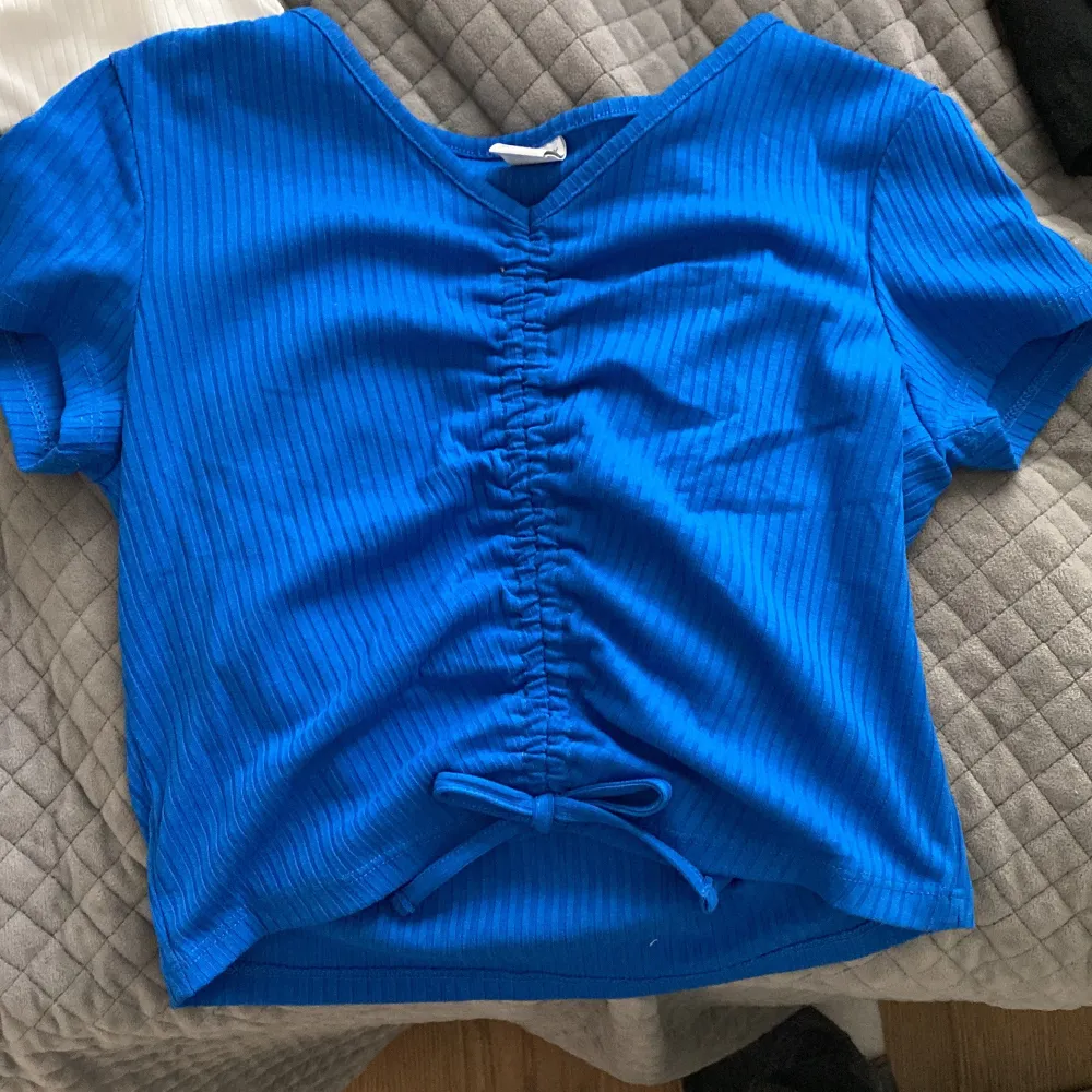 Blå T-shirt med en v ring. Säljer pga att det inte är min stil och den kommer aldrig till andvändning.OBS köpare står för frakt.. T-shirts.