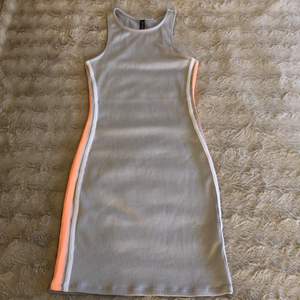 En ljusgrå åtsittande klänning från H&M.🛍 Har aprikos/neon & vita ränder på sidorna.🤍