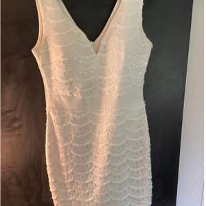 En vit klänning med V-ringning. Den har en liten sminkfläck på ”kragen” med det syns inte direkt.  (Köparen står för frakt) 