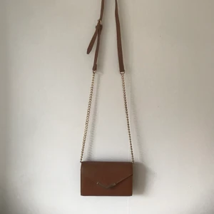 Brun väska - Brun handväska med gulddetaljer. I princip helt orörd.  Många fack för förvaring, perfekt när man bara vill ha med sig det mest nödvändiga.