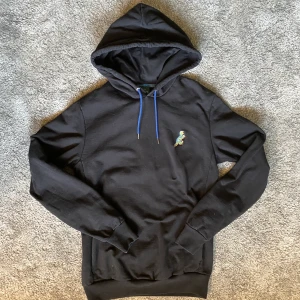 Paul Smith hoodie  - Paul Smith Dino-hoodie. Knappt använd hoodie från klädesmärket Paul Smith. Denna är en exklusiv tröja från deras Dinokollektion. Hög kvalite, 100% organisk bomull.  Storlek XS (herr), kan även passa S   Nypris 960 kr  Köparen står för frakt 