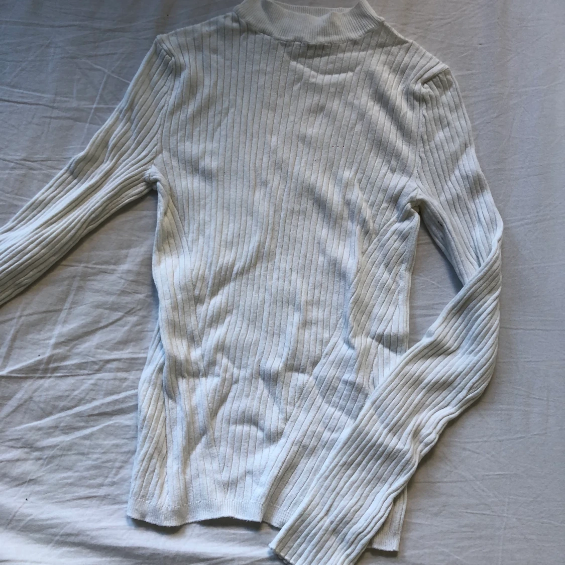 Vit räfflad tröja med högre hals. 