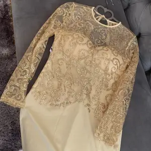 En super fin klänning från Dennis Marglic i guld med guld glitter. Klänningen är lite längre och är öppen i ryggen. 