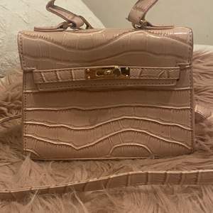 Säljer en söt rosa handväska med guld detaljer som är i bra skick, den är mellan stor och har en ficka inne i väskan så den är ganska rymlig.💗
