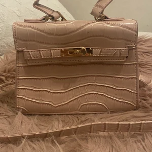 Rosa handväska - Säljer en söt rosa handväska med guld detaljer som är i bra skick, den är mellan stor och har en ficka inne i väskan så den är ganska rymlig.💗