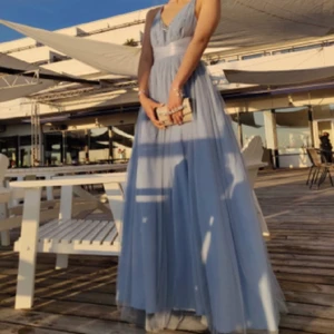 Balklänning Ljusblå - Balklänning i väldigt fint skick. Snörning i midjan och dragkedja i ryggen. Använd två gånger, en gång av förra ägaren (som även sydde in lite stenar där fram) och en kväll av mig. Det finns inga hål, fläckar eller andra fel. Kan skickas mot att köparen betalar frakt. Storlek S.