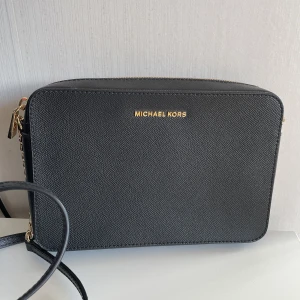 Michael Kors crossbodie - Säljer min äkta Michael Kors crossbodie som jag endast använt en gång. Den köptes på Nelly.com Dragkedjan är något trög men det har den alltid varit, annars är den i toppskick! Köptes för 1499 kr