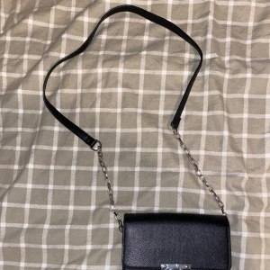 En svart liten väska  - En svart liten söt axel väska  som passar bra till alla outfits. Du kan även själv justera längden på väskan upp till silver kedjan