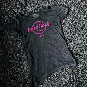 N Hard Rock Cafe T-shirt Ibiza orginal. Lite längre på ena sidan ner till för att man ska kunna knyta den i midjan. Tunt tygg. Rosa tryck. Fattas en liten pärla i trycket. Annars hel och ren.