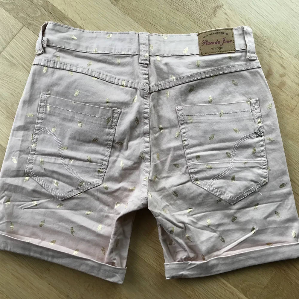 Ljusrosa shorts med guldfjädrar på. Har tyvärr aldrig kommit till användning, bara provade.. Shorts.