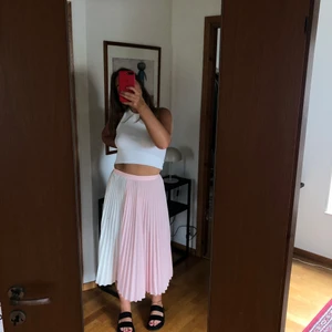 Refflad kjol - Refflad kjol i två olika färger, rosa och vit. Endast använd en gång! Den har en dragkedja som man knäpper den med och är alltså inte töjbar i midjan