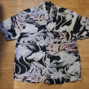 Kortärmad skjorta  - En somrig kortärmad skjorta från H&M's herravdelning, aldrig använd och köpt förra sommaren:) tryck et är typ diffusa palmer lch hav o pastellfärger 