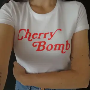 Cherry Bomb T-shirt  Tjej-modell i 100% bomull, 145g/m2 säljes. Made in Sweden! Limiterad antal! Ingen Massproduktion.  Bystmått : 49cm  Längd ( baksida ) : ca 60cm More sizes at elcamelloshop.com 