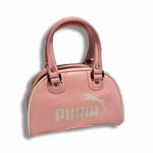 Rosa Puma mini väska - As söt rosa pumaväskan. Lite smutsig men i framsidan men får lätt att ta bort det men en blöt tras. Den är lite för tajt för att kunna använda på axeln då den är till barn