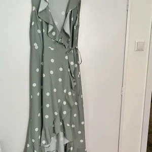 Prickig grön omlottklänning - Superfin grön klänning köpt i Berlin för två år sedan. Har ingen användning för den längre. Frakt betalas av köpare.