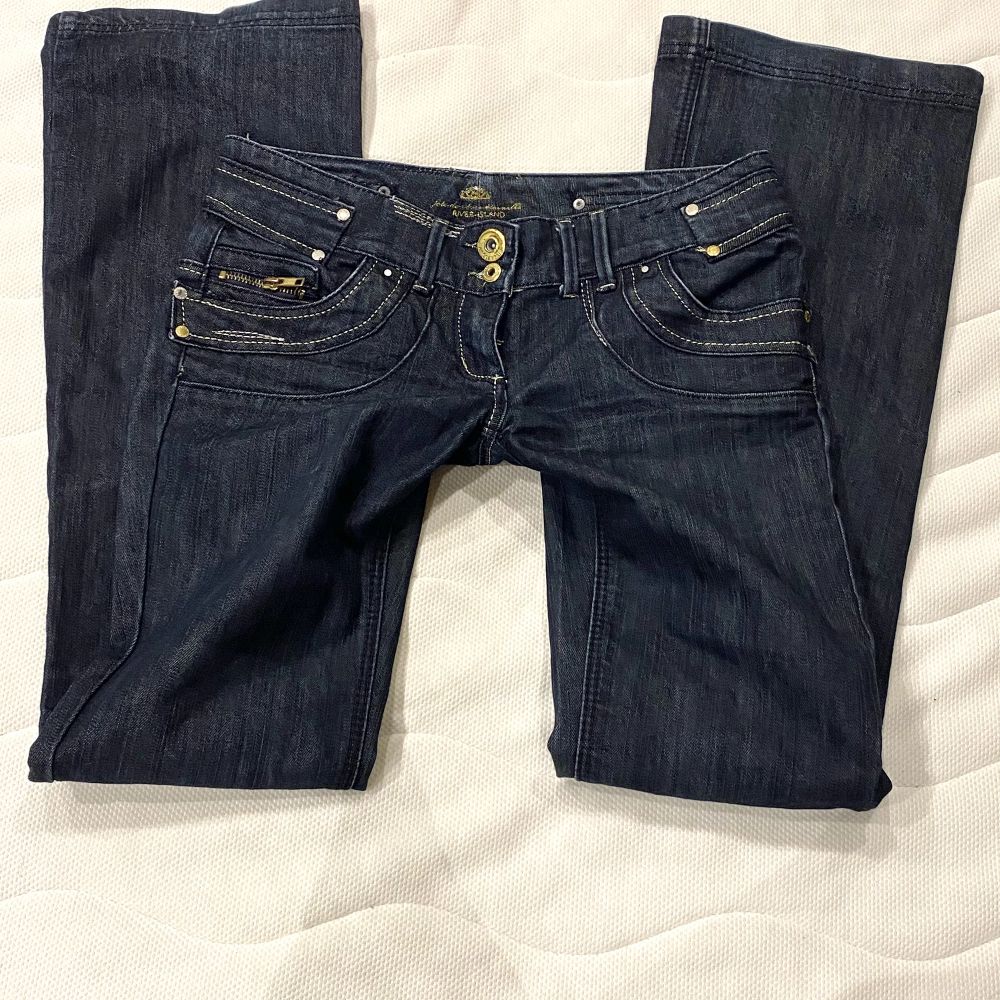 Lågmidjade jeans med sjukt coola bakfickor. Jeansen är utsvängda/raka och har många guld detaljer. Dom är i bra skick har inga hål, fläckar osv. Innerbenslängd: 83cm Midjemått: 40cm Köpare står för frakten💗. Jeans & Byxor.
