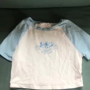 En bekväm vit croptop med blåa armar med texten angel baby 