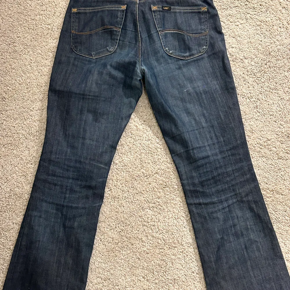 Säljer mina lågmidjade straight/lite utsvängda lee jeans i mörk tvätt, då de blivit för små. Sjukt snygga och speciella! Lite slitna vid rumpan som, men endast det som syns på bilden. Midjemått 38 cm, innerben 78 cm.. Jeans & Byxor.