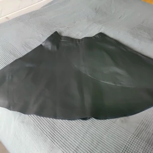 Kjol i läderimitation från Amisu - Svart kjol i läderimitation strl 40 från Amisu säljes. I fint skick. Förgåtergivning på bilden är blekare än varan är irl. Endast provad. Tvättad. Knälängd. Material är 100% polyester. Kommer från djur och rökfritt hem. Frakt betalas av köpare. Om man vill ha annat fraktalternativ så går det att ordna. Betalning sker via Swish och varan skickas så fort betalningen inkommit. Jag ansvarar inte för postens slarv. Bud är bindande. Samfraktar gärna.