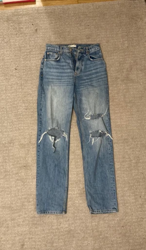 Jeans blåa  - Jeans mid-waist med hål vid knäna, från Gina tricot, i strl 34 men kan passa en 36 också. ställ frågor om ni har några, elr om ni vill ha mer bilder💗 
