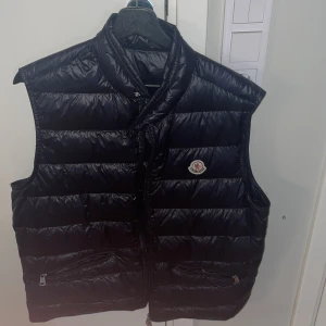 Moncler Gui Vest Mörkblå - Storlek 4/L. Passar M och L. Riktigt snygg väst till både våren och sommaren. Perfekt mörklblå färg som kan matcha med alla typer av kläder. Köpt på Moncler butiken i Stockholm för 5500kr. Helt ny. Kvitto kan uppvisas. Hör av dig vid intresse!