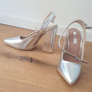 Silver shoes with thick 14cm high heels and pointed toes.