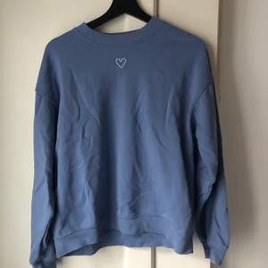 Sweater från Monki • strl S - Blå sweater med litet broderat hjärta. Knappt använd och är i fint skick. Storlek S men passar även personer med storlek M