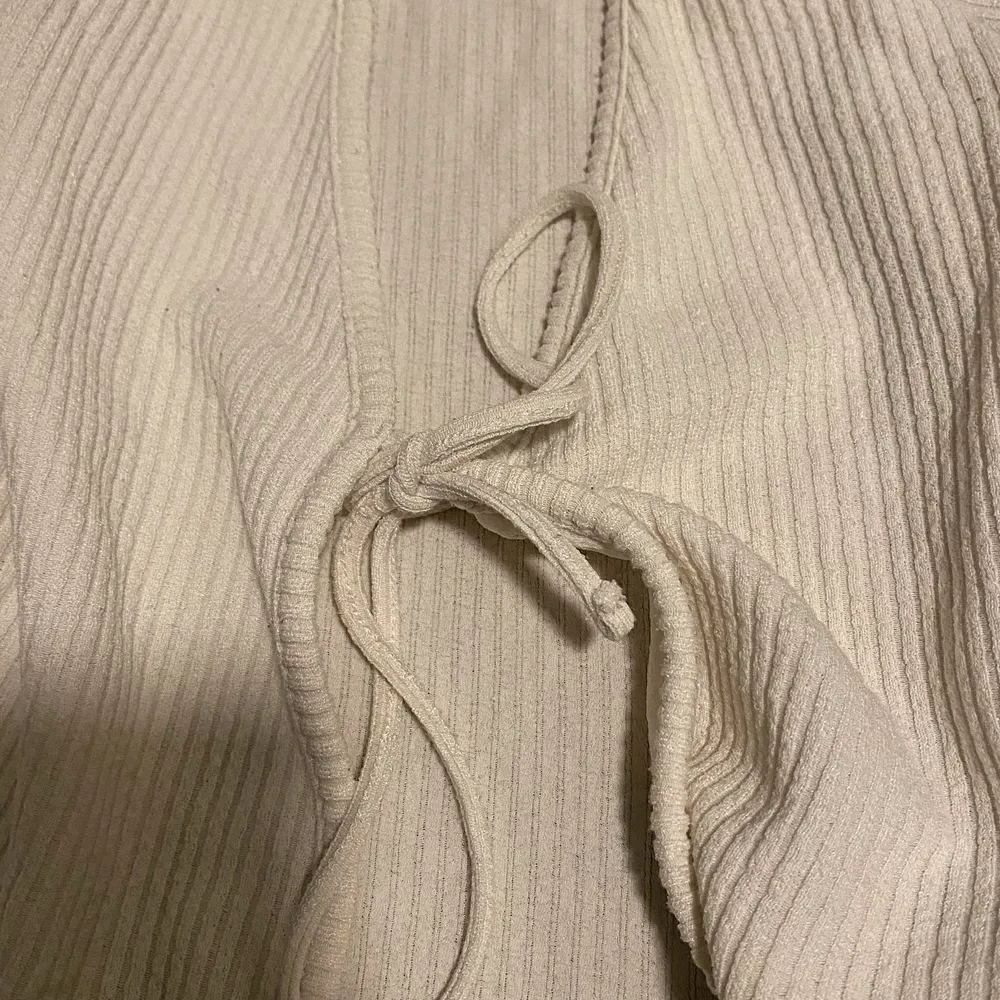 En vit blus/kofta som du kan knyta i mitten, fint att ha en tröja under. Tunnt och fräscht tyg. ( det finns ett litet hål på sidan av blusen/koftan) . Tröjor & Koftor.