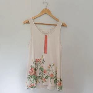 Blommig top - En blommig top med dekorativ dragkedja. Storlek L 95% viskos och 5% elastan.