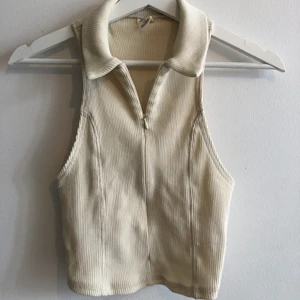 Urban outfitters topp beige - Fin topp från urban outfitters med dragkedja framtill som kan ge en djup uringning eller dras upp helt. Nyskick och säljer för att det tyvärr är för litet för mig. Storlek L men skulle säga att det mer passar M/S