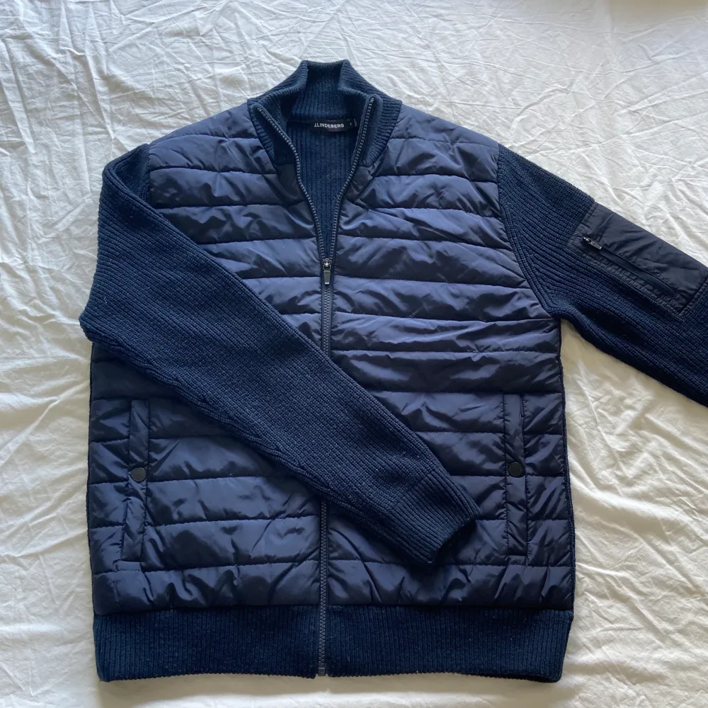 J Lindeberg Hybrid (cardigan) Jacket. Knappast använd men har legat i garderoben ett tag men är i bra skick, inga flaws eller liknande.  Storleken är medium, säljes för 999kr + porto. Jackor.