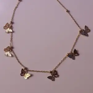 Sött guldhalsband med fjärilar, kan skicka som brev för 15kr. Första bilden visar färgen korrekt, de två andra bilderna visar hur det sitter som kortast och som längst