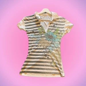 T-shirt/polotröja med blommor - Säljer denna jättefina tshirten med fina detaljer och rhinestones🌟🌟 Jag har sytt in den själv men de är bra gjort och den sitter därför superfint! Jag har köpt den secondhand men använt fåtal ggr och den är i bra skick! Hör av er vid intresse💞💞
