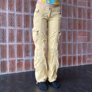 Cargobyxor - Unika lågmidjade ljusgula cargobyxor. Väldigt bra skick! Storlek 28. Mått ~ runt midjan 81.5 cm, innerbenslängd 89 cm. Frakt tillkommer😽