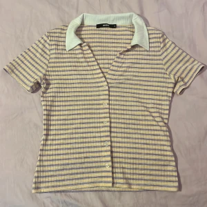 T-shirt från bikbok  - En fin lila, gul och vit randig tröja från Bikbok med knappar i fram och en vit krage. Den är strl M men är stretchig så skulle säga XS-M beroende på passformen man vill ha. Jag har XS eller S så den är lite lös på mig. 