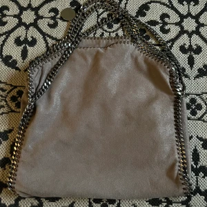 Stella McCartney falabella väska  - Säljer min äkta stella McCartney väska som är i färgen ”taupe” superfin färg och väskan är i fint skick! Den är köpt i london 2018 för 850£. Är även öppen för byten mot en svart mellan falabella stella väska! ❤️‍🔥klicka ej på köp direkt🥰