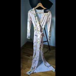 Sommarklänning Nelly - Fin blommig långklänning med slits och knytning. Aldrig använd. Skriv i chatt vid intresse, möts upp i Hägersten.