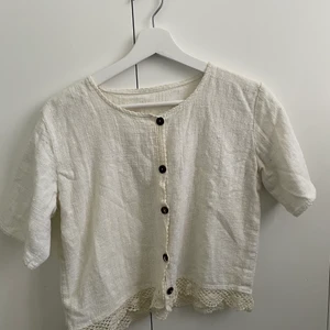 Kroppad blus i linne, stl s - Spetsdetaljer nertill och fina bruna träknappar, så söt! 