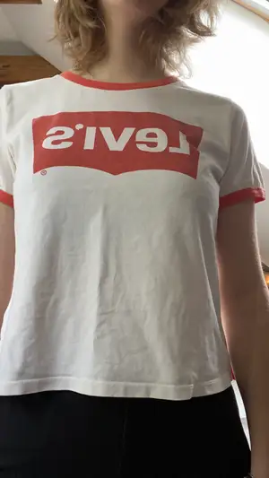En vit Levi’s T-shirt med röda detaljer. Storlek: M. Plagget är lite använt och är cirka 4 år gammalt.