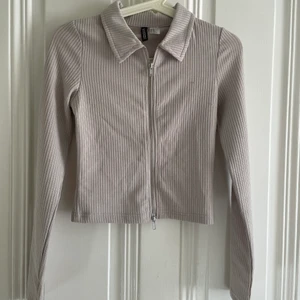 Dragkedja tröja  - Säljer en super fin topp från H&M men en justerbar dragkedja, färgen är grå beige. Kommer tyvärr inte till användning storlek XS! 