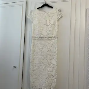 Oanvänd vit spets klänning från Nelly, ej genomskinlig med två lager, knälängd.