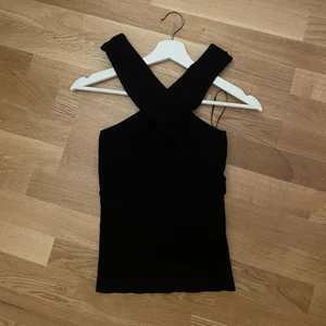 Svart topp - Topp från zara som korsas vid halsen. Så fin men kommer inte till användning vilket gör att den är som ny i kvaliten! Strl M men passar mig som brukar ha S i toppar❤️ hör av er vid frågor 🥰 frakt tillkommer!