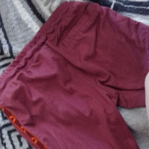 Puma - Dom är lite mer vinröda än på bilden. Dragkedjor längs ner med benen och en ficka back och två fickor fram. Självklart är som äkta, köpt på stadium. Väldigt bekväma 