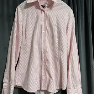 Rosa och vit randig Gant skjorta. Använd väldigt fåtal gånger så fortfarande i bra och fint skick. I skjortan står det storlek 40 men skulle säga att den är som en storlek S. Pris kan diskuteras. Köparen står för frakten. Betalning sker via Swish. 