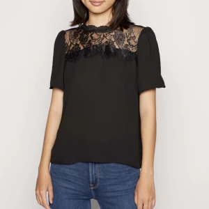 Svart topp med spets  - Jättefin svart blus i nyskick! Säljs då den inte kommer till användning. Nypris 299