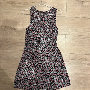 Blommig klänning  -  Klänning med cut out på magen.  Står storlek 38 men mer som 36.  Mycket fint skick. 