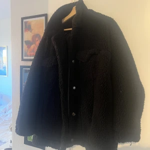 Teddyjacka svart - Säljer min mysiga, fodrade teddyjacka från Monki i storlek L. Den slutar ca 10 cm nedanför höfterna på mig som är 160, har fyra fickor och knappar.