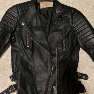 Chiquelle skinnjacka  - Den otroligt populära chiquelle skinnjackan i svart läderimitation. Använd väldigt fåtal gånger, i strl 36, en ganska slimfit modell. 