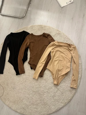 Body - Säljer 3 stycken Bodies då de ej kommer till användning. Finns i beige, brun och svart. Storlek m. Aldrig använda. stretchigt material. 120kr styck eller alla för 300kr