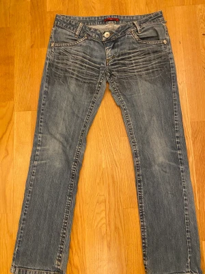 Lågmidjade jeans  - Lågmidjade jeans från märket Angel Devil. Rak modell med detaljer. En hälla bak är sönder annars bra skick 💗